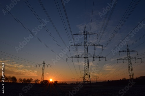 Sonnenaufgang an einem Feld mit Strommasten