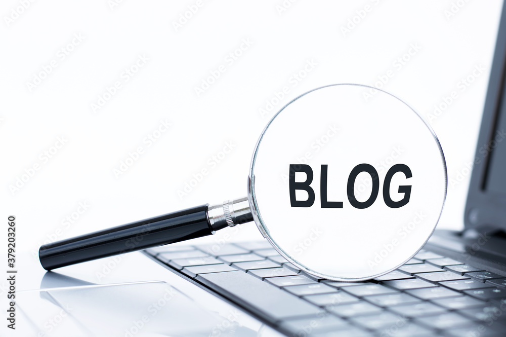 Blog text on a magnifying glass lying on a laptop keyboard. Blog text on a magnifying glass lying on a laptop keyboard.