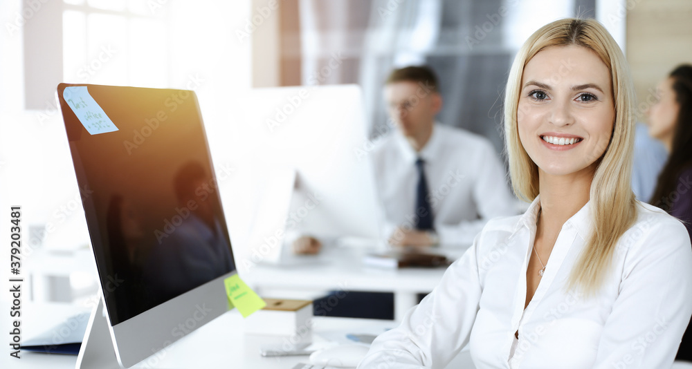 Blond business woman using computer at workplace in sunny office. Working for pleasure and success Blond business woman using computer at workplace in sunny office. Working for pleasure and success