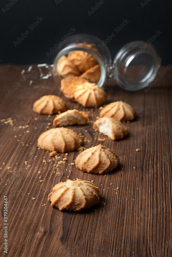 Cookies fall out of the glass jar on a wooden table