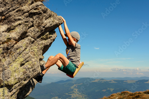 The boy is engaged in mountaineering, a child climbing a rocky mountain, a brave boy. © Niko_Dali