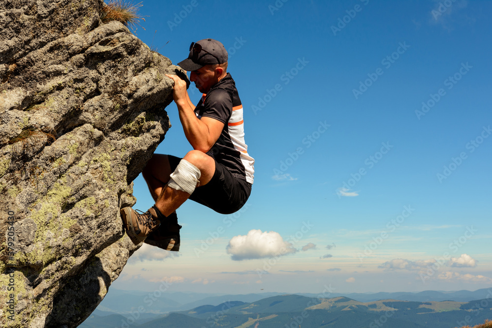The man is engaged in mountaineering, climbs to the top, an epic view of the climber against the sky and mountains.