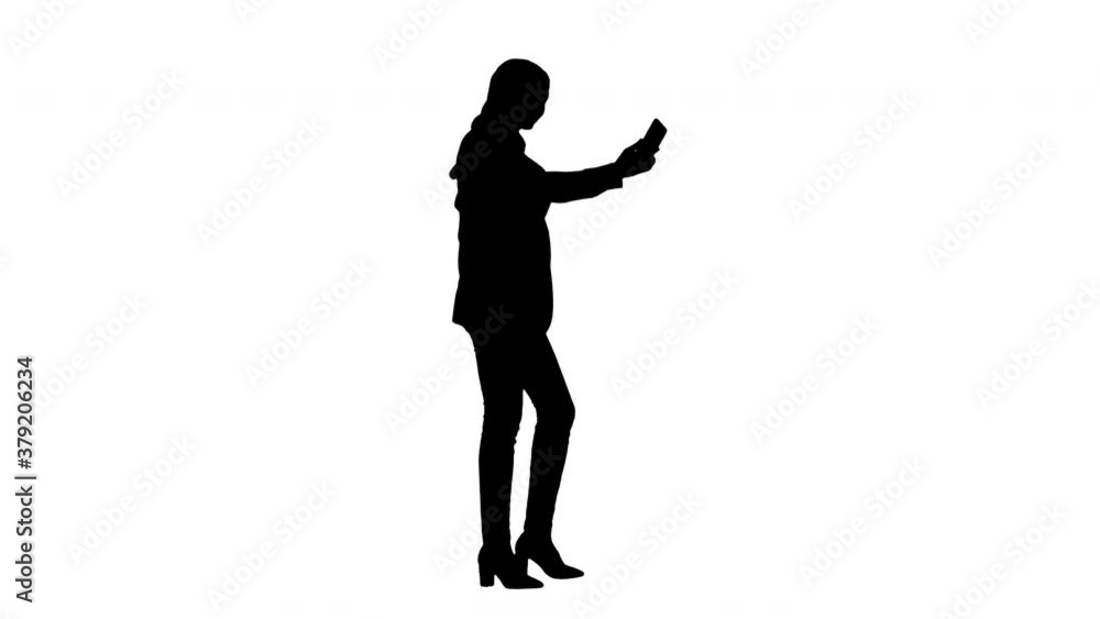 Silhouette Young pretty muslim woman in hijab having video call on her phone as she walks. Silhouette Young pretty muslim woman in hijab having video call on her phone as she walks.