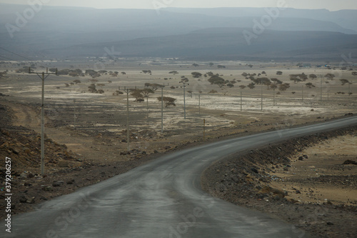 asphalt road leads down the hill through the desert