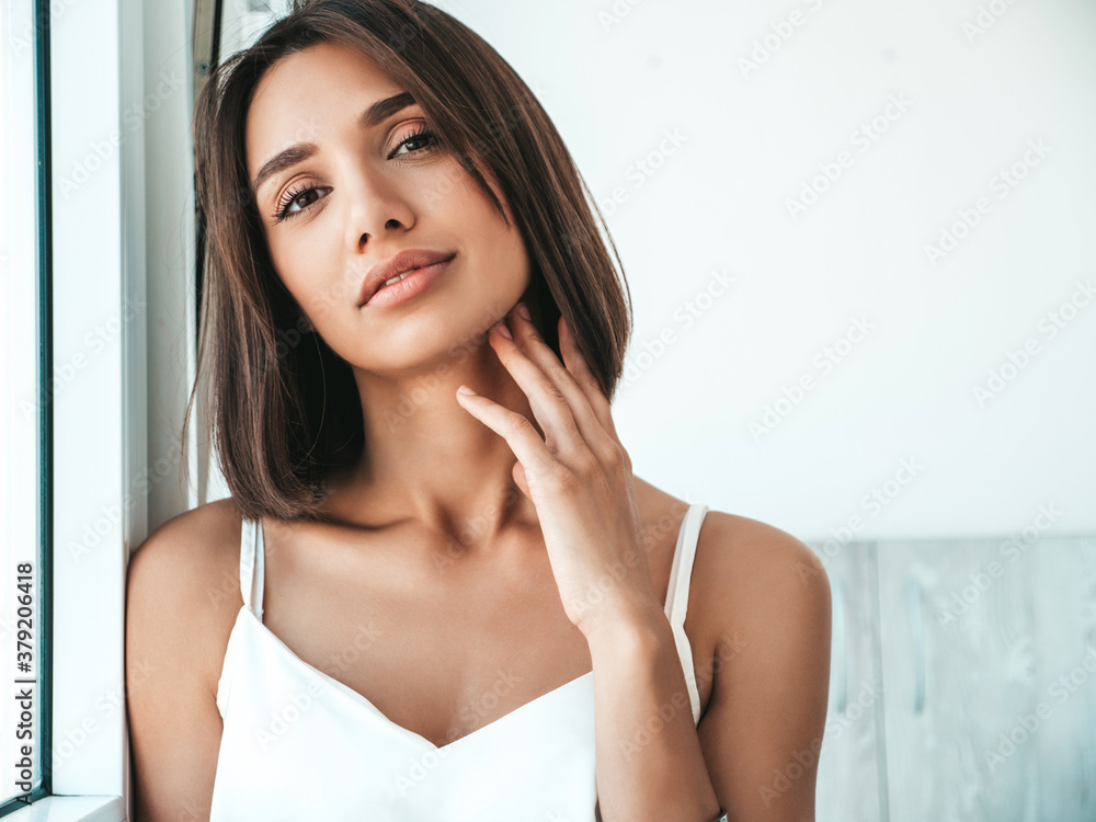 Portrait of beautiful woman dressed in white pajamas. Sexy carefree model enjoying her morning at balcony. Female looking at camera Portrait of beautiful woman dressed in white pajamas. Sexy carefree model enjoying her morning at balcony. Female looking at camera