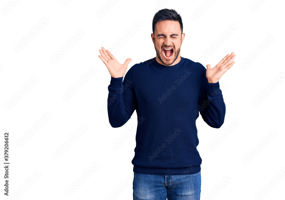 Fototapeta premium Young handsome man wearing casual clothes celebrating mad and crazy for success with arms raised and closed eyes screaming excited. winner concept