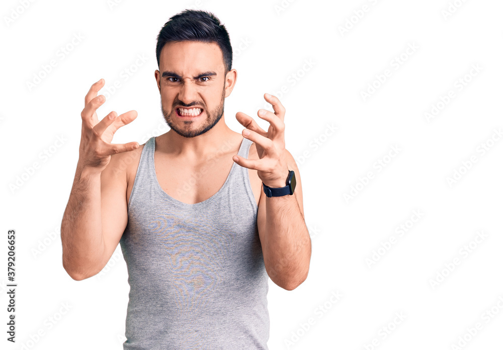 Fototapeta premium Young handsome man wearing swimwear and sleeveless t-shirt shouting frustrated with rage, hands trying to strangle, yelling mad