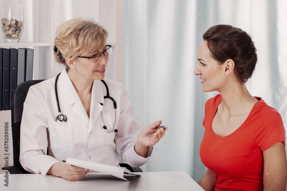 Pretty young patient in medical office of helpful senior female doctor Pretty young patient in medical office of helpful senior female doctor