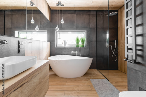 Stylish bathroom with wooden and concrete walls and white bath