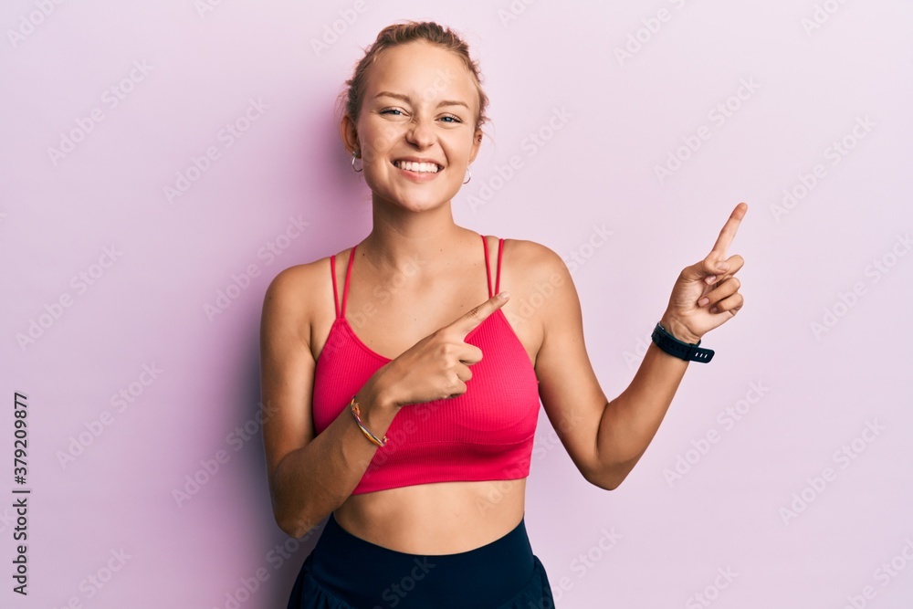 Beautiful caucasian woman wearing sportswear smiling and looking at the camera pointing with two hands and fingers to the side. Beautiful caucasian woman wearing sportswear smiling and looking at the camera pointing with two hands and fingers to the side.
