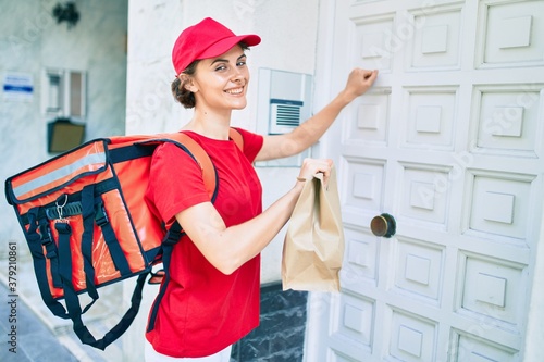 Delivery business worker woman wearing uniform smiling happy knocking on the door photo