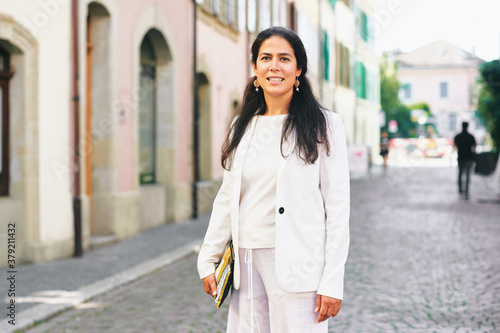 Beautiful middle age woman posing outside, wearing white jacket