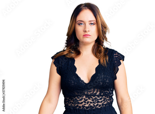 Young beautiful caucasian woman wearing elegant dress with serious expression on face. simple and natural looking at the camera.