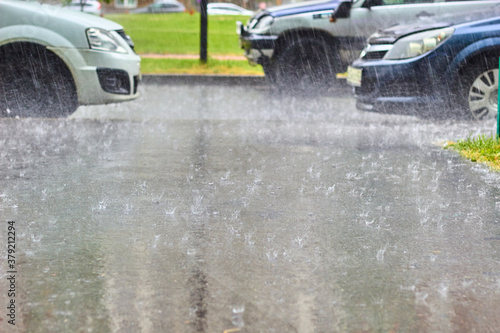 heavy downpour splashes of drops on the asphalt on the background of cars