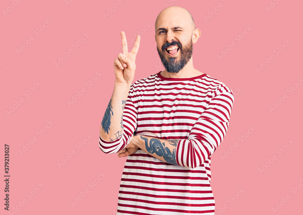 Fototapeta premium Young handsome man wearing casual clothes smiling with happy face winking at the camera doing victory sign. number two.