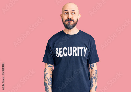 Bild auf Leinwand Young handsome man wearing security t shirt puffing cheeks with funny face