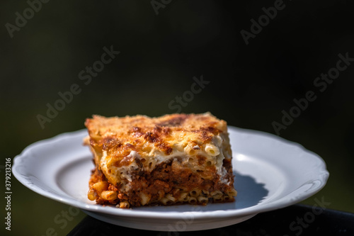 Preparing traditional greek food recipe. Baked pasta casserole pastitsio with rich bechamel sauce and ground beef.