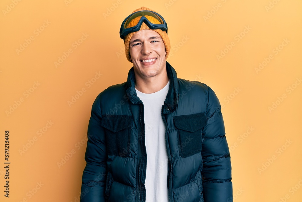 Fototapeta premium Handsome caucasian man wearing snow wear and sky glasses with a happy and cool smile on face. lucky person.