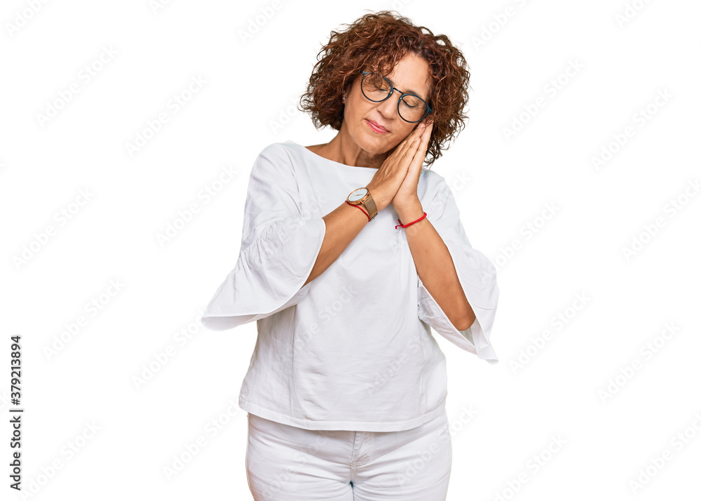 Beautiful middle age mature woman wearing casual clothes and glasses sleeping tired dreaming and posing with hands together while smiling with closed eyes. Beautiful middle age mature woman wearing casual clothes and glasses sleeping tired dreaming and posing with hands together while smiling with closed eyes.