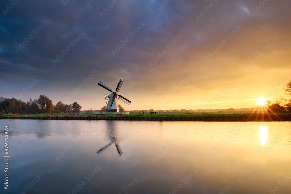 beautiful sunrise over Dutch windmill by river