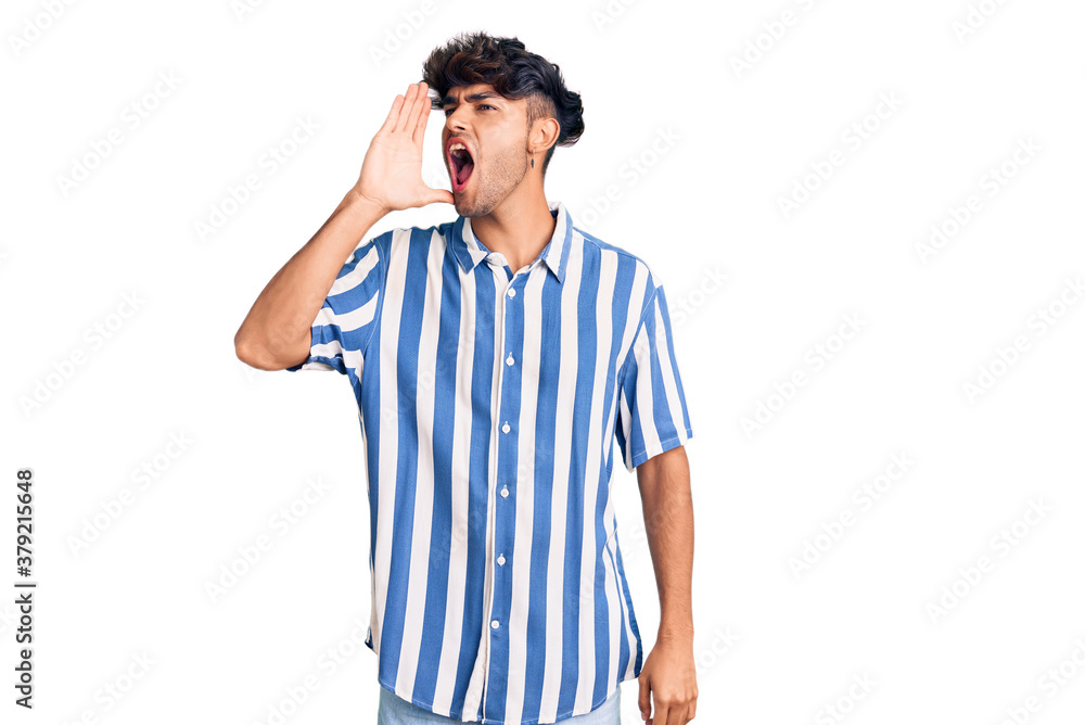 Young hispanic man wearing casual clothes shouting and screaming loud to side with hand on mouth. communication concept. Young hispanic man wearing casual clothes shouting and screaming loud to side with hand on mouth. communication concept.