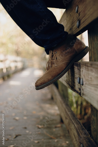 man with boots on wooden fence