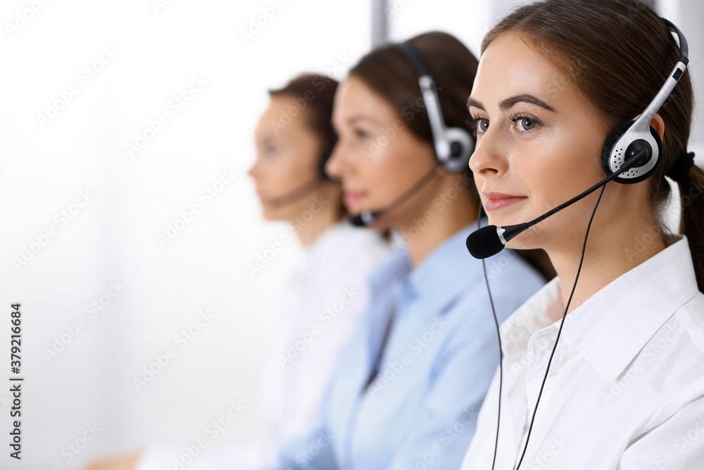 Call center. Group of operators at work. Focus at beautiful business woman in headset Call center. Group of operators at work. Focus at beautiful business woman in headset