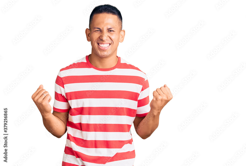 Young handsome latin man wearing casual clothes excited for success with arms raised and eyes closed celebrating victory smiling. winner concept. Young handsome latin man wearing casual clothes excited for success with arms raised and eyes closed celebrating victory smiling. winner concept.