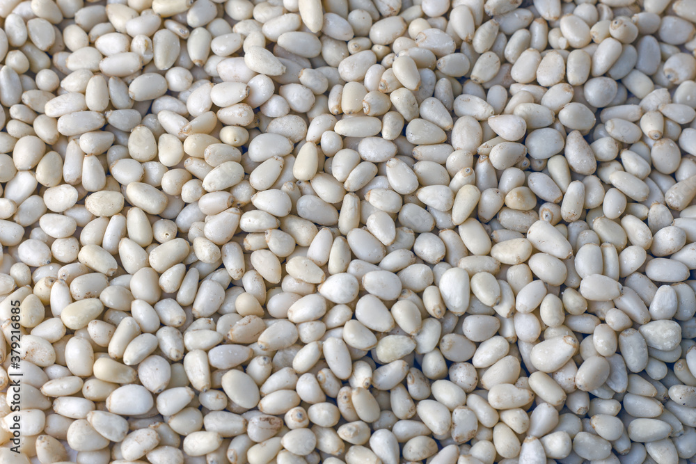 a pile of scattered peeled kernels of ready-to-eat pine nuts on a table a pile of scattered peeled kernels of ready-to-eat pine nuts on a table