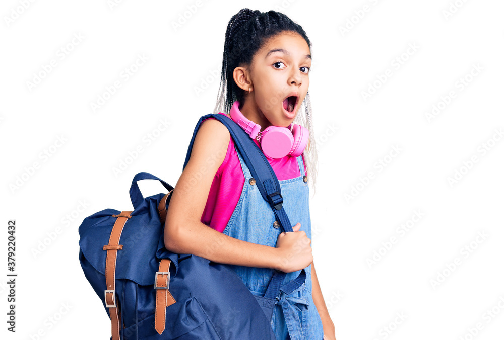 Cute african american girl holding student backpack using backpack scared and amazed with open mouth for surprise, disbelief face Cute african american girl holding student backpack using backpack scared and amazed with open mouth for surprise, disbelief face