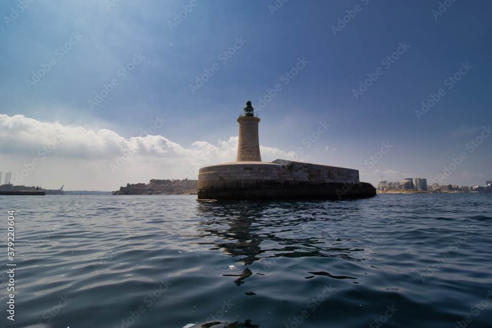 lighthouse by valetta city. ligthouse at sea. Grand Harbor at the City of Valletta, Malta. boatt background lighthouse by valetta city. ligthouse at sea. Grand Harbor at the City of Valletta, Malta. boatt background