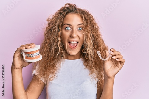 Beautiful caucasian teenager girl holding invisible aligner orthodontic and braces celebrating crazy and amazed for success with open eyes screaming excited.
