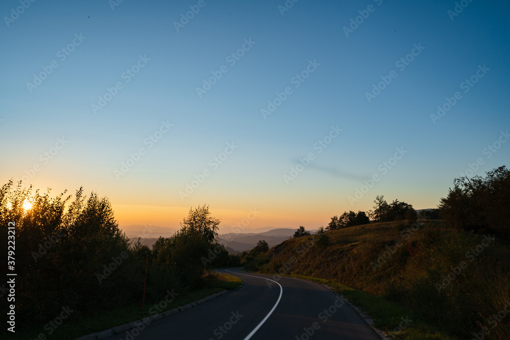Mountain landscape in sunrise or sunset dark hills with golden sun and blue sky - Road in nature with trees on stara planina Old Mountain in Serbia - tourist destination and freedom concept