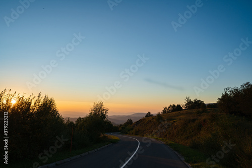 Mountain landscape in sunrise or sunset dark hills with golden sun and blue sky - Road in nature with trees on stara planina Old Mountain in Serbia - tourist destination and freedom concept