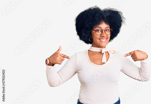 Young african american girl wearing casual clothes and glasses looking confident with smile on face, pointing oneself with fingers proud and happy.