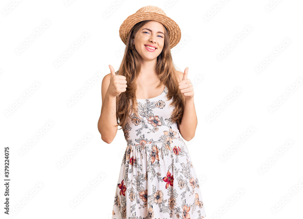 Beautiful caucasian young woman wearing summer hat success sign doing positive gesture with hand, thumbs up smiling and happy. cheerful expression and winner gesture. Beautiful caucasian young woman wearing summer hat success sign doing positive gesture with hand, thumbs up smiling and happy. cheerful expression and winner gesture.
