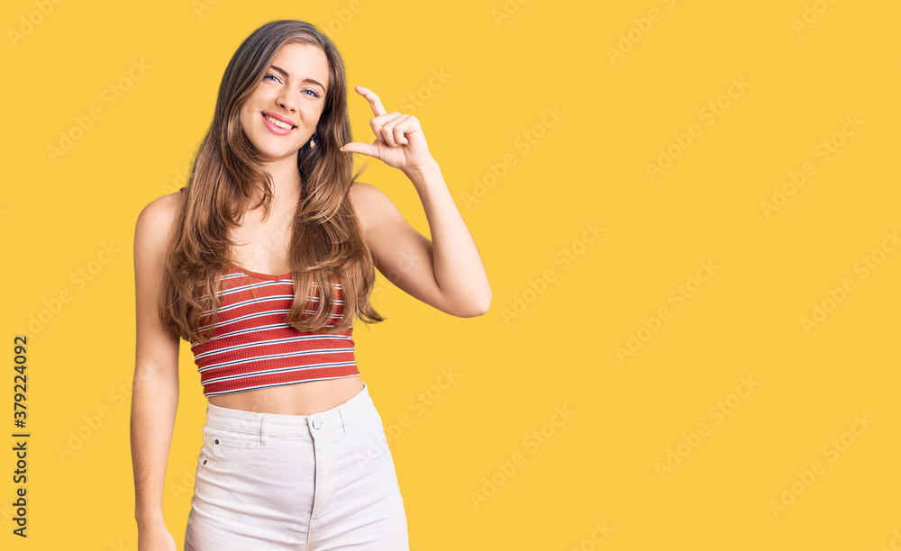Beautiful caucasian young woman wearing casual clothes smiling and confident gesturing with hand doing small size sign with fingers looking and the camera. measure concept. Beautiful caucasian young woman wearing casual clothes smiling and confident gesturing with hand doing small size sign with fingers looking and the camera. measure concept.