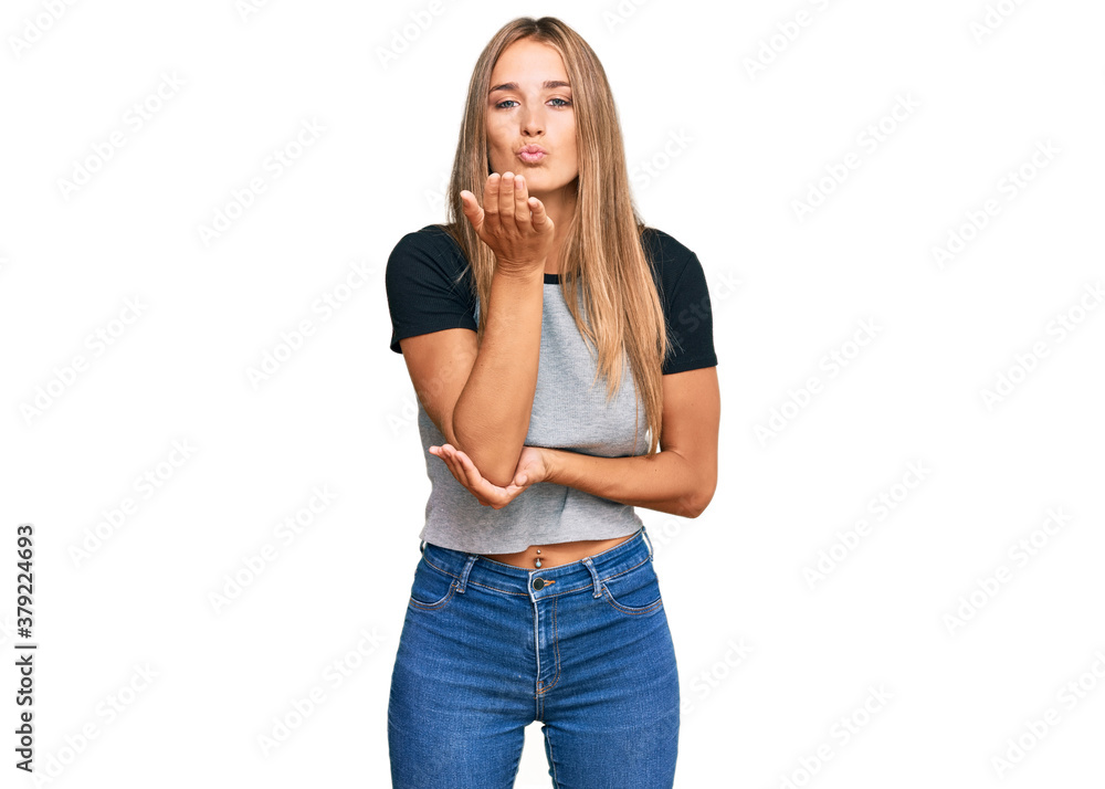 Young blonde woman wearing casual clothes looking at the camera blowing a kiss with hand on air being lovely and sexy. love expression. Young blonde woman wearing casual clothes looking at the camera blowing a kiss with hand on air being lovely and sexy. love expression.