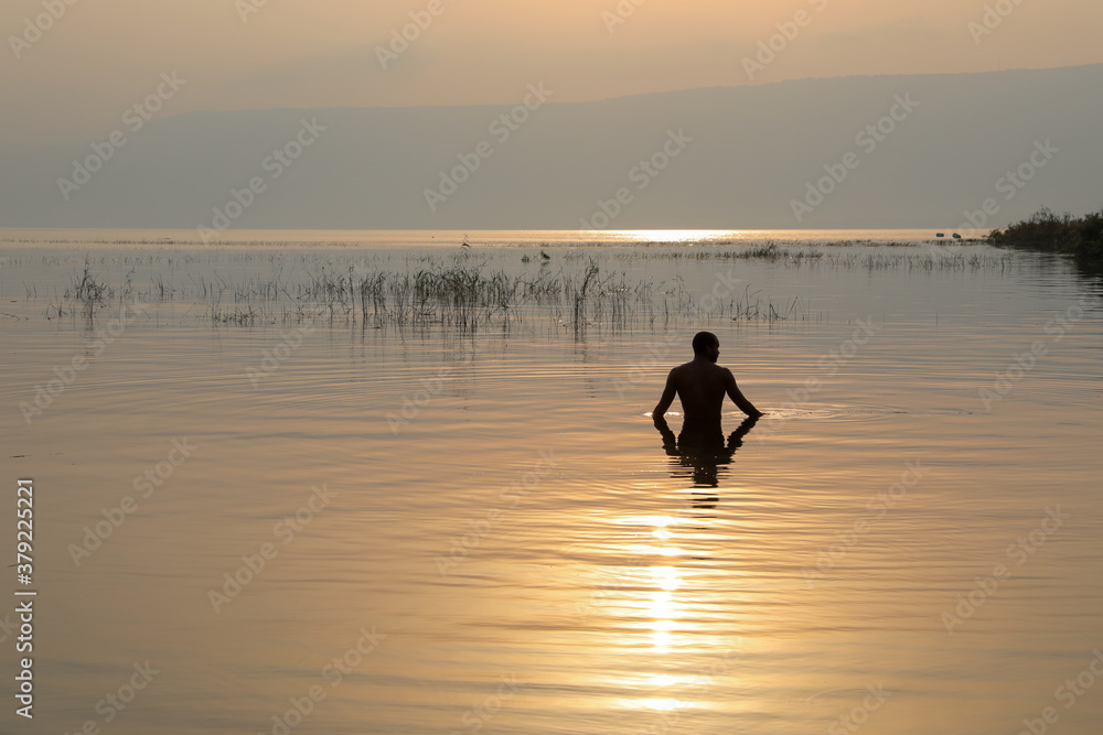 Man dipped in the water of Galilee Lake in Israel at sunrise.