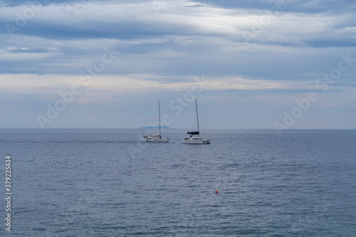 White sailboats sailing around Hvar island, popular nautical and tourist destination in the Dalmatian sea during cloudy day over sea © Miroslav Posavec