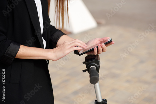 Hands of young female in black cardigan scrolling in smartphone over panel