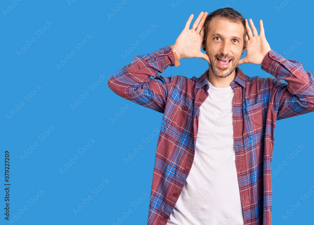 Young handsome man wearing casual clothes smiling cheerful playing peek a boo with hands showing face. surprised and exited Young handsome man wearing casual clothes smiling cheerful playing peek a boo with hands showing face. surprised and exited