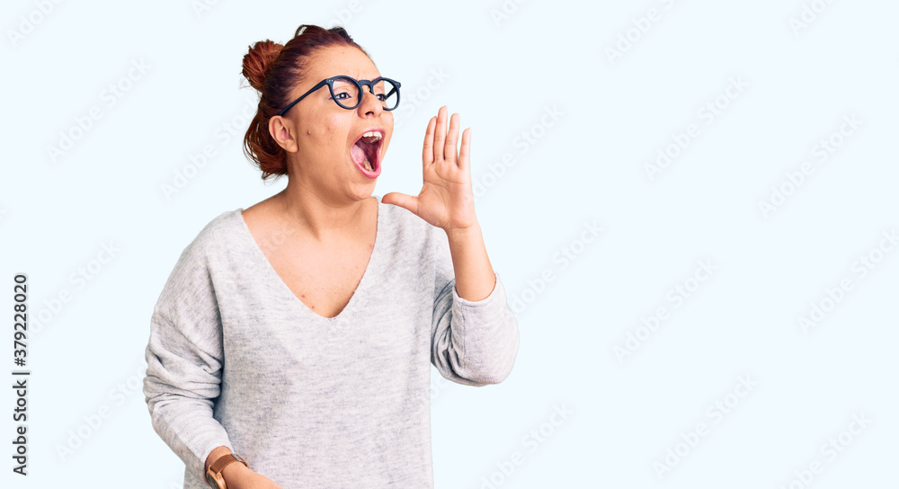 Young latin woman wearing casual clothes shouting and screaming loud to side with hand on mouth. communication concept. Young latin woman wearing casual clothes shouting and screaming loud to side with hand on mouth. communication concept.