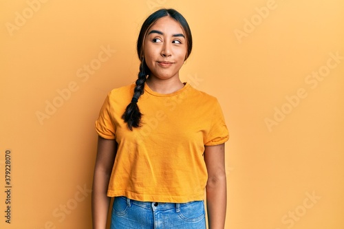 Young latin woman wearing casual clothes smiling looking to the side and staring away thinking.