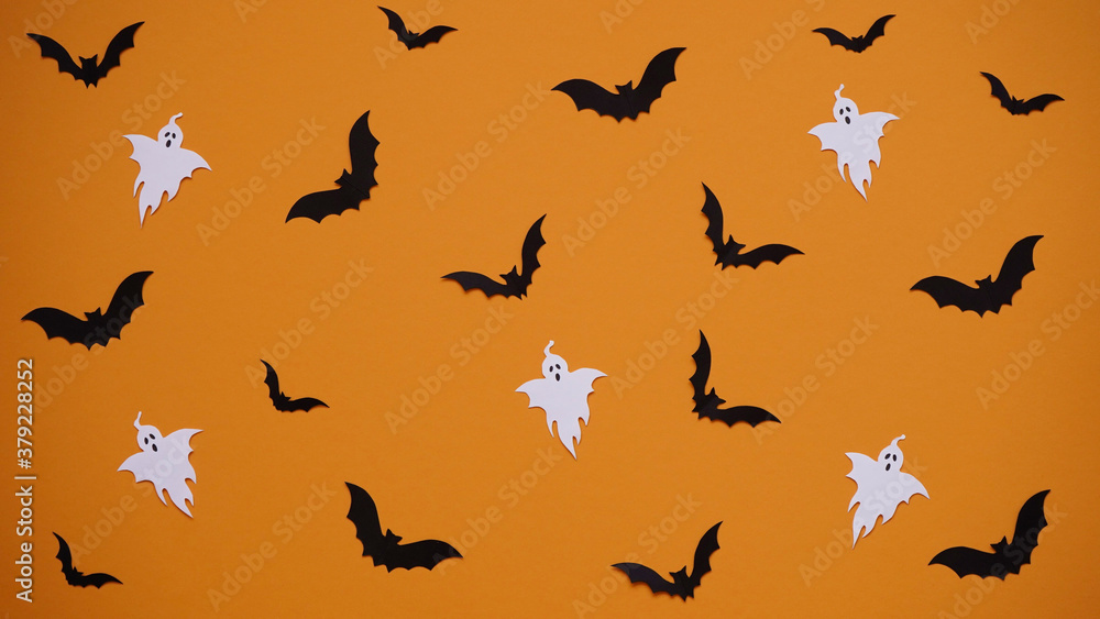 Halloween decoration concept - seamless pattern with black paper bats and ghosts on orange background, flat lay.Celebration of the dead