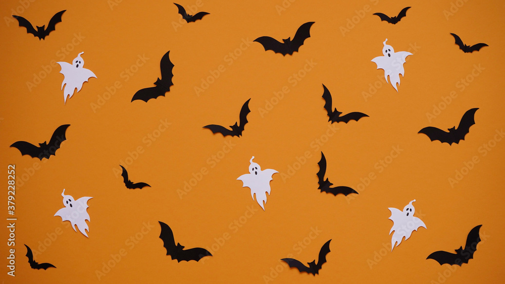 Halloween decoration concept - seamless pattern with black paper bats and ghosts on orange background, flat lay.Celebration of the dead Halloween decoration concept - seamless pattern with black paper bats and ghosts on orange background, flat lay.Celebration of the dead