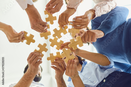 Positive company workers playing with jigsaw puzzle during team building activity photo