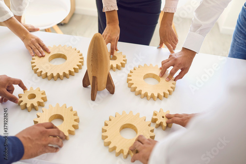 Businesspeople around office table with rocket and cogwheels deciding on company strategy