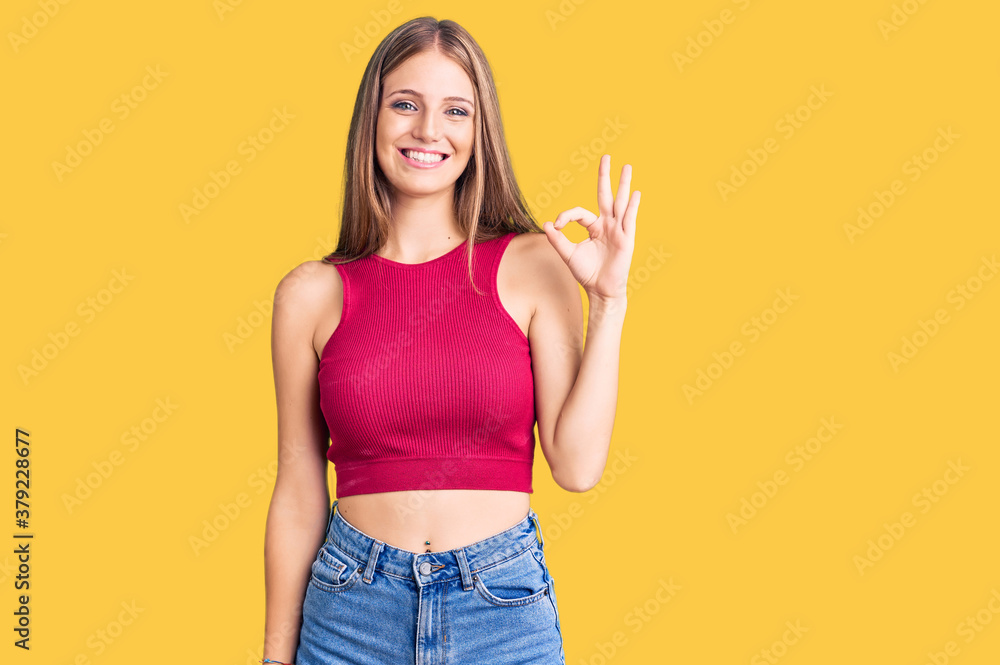 Young beautiful blonde woman wearing elegant summer shirt smiling positive doing ok sign with hand and fingers. successful expression. Young beautiful blonde woman wearing elegant summer shirt smiling positive doing ok sign with hand and fingers. successful expression.