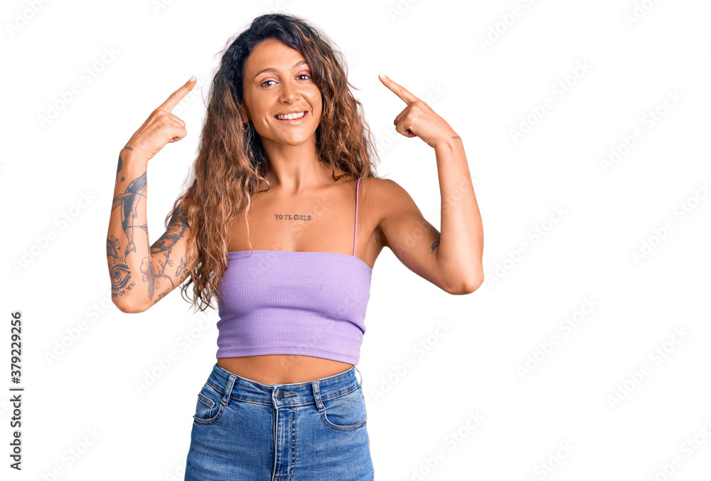 Young hispanic woman with tattoo wearing casual clothes smiling pointing to head with both hands finger, great idea or thought, good memory Young hispanic woman with tattoo wearing casual clothes smiling pointing to head with both hands finger, great idea or thought, good memory